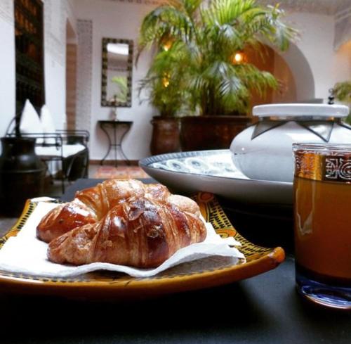 a plate of bread on a table with a drink at Riad Les Nuits de Marrakech in Marrakech