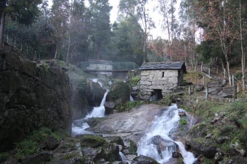 a waterfall in a forest with a bridge and a river at Casa Valxisto in Penafiel