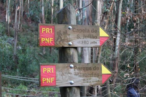 two wooden signs on a pole in a forest at Casa Valxisto in Penafiel