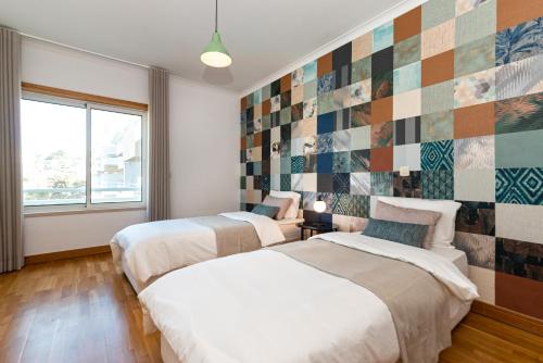 2 łóżka w sypialni ze ścianą wyłożoną kafelkami w obiekcie Bafureira Cascais Apartment; Condomínio privado com piscina w mieście Parede