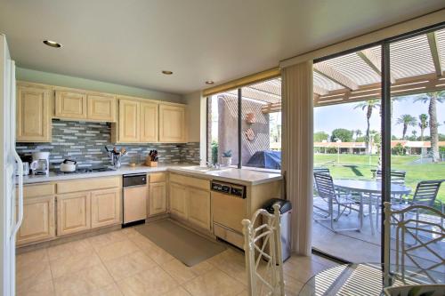 a kitchen with wooden cabinets and a patio with a table at Indian Wells Desert Paradise with Mtn View and Patio! in Indian Wells