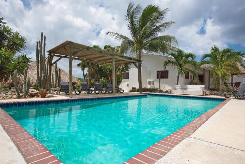 a swimming pool with a gazebo and palm trees at Bantopa Apartments in Willemstad