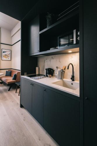 a kitchen with black cabinets and a white sink at Getaway Studios Gent in Ghent