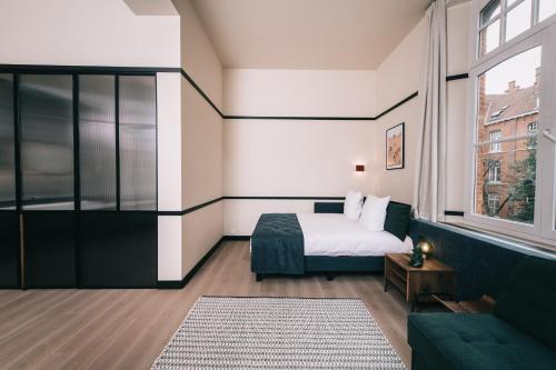 a bedroom with a bed and a couch and a window at Getaway Studios Gent in Ghent
