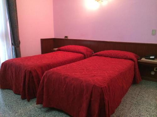 two beds in a room with red sheets at Re Di Cuori Hotel in Caianello