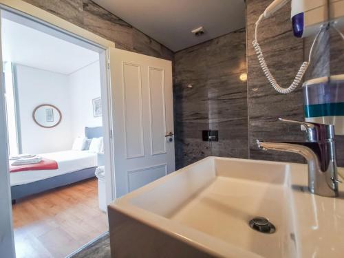 a bathroom with a sink and a bedroom with a bed at Fanqueiros Apartment in Lisbon