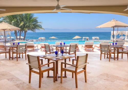 a restaurant with tables and chairs next to the ocean at Casa Velas Adults Only All Inclusive in Puerto Vallarta