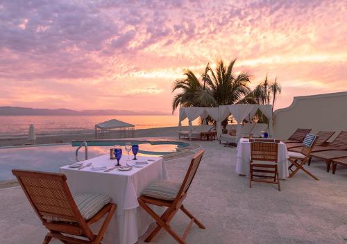 a restaurant with tables and chairs next to a pool at Casa Velas Adults Only All Inclusive in Puerto Vallarta