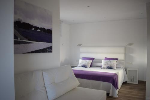 1 dormitorio con cama con sábanas moradas y sofá en Hotel Restaurante Racha, en Endrinal