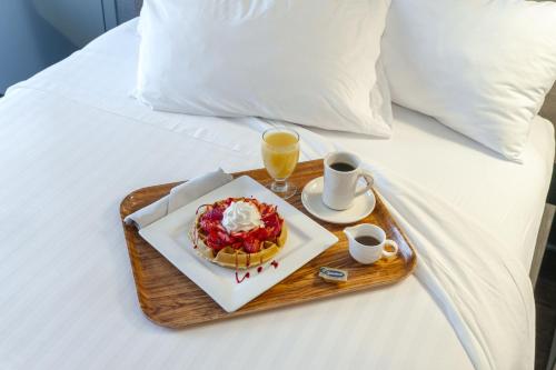 a tray with a waffle and a drink on a bed at RIT Inn & Conference Center in Henrietta