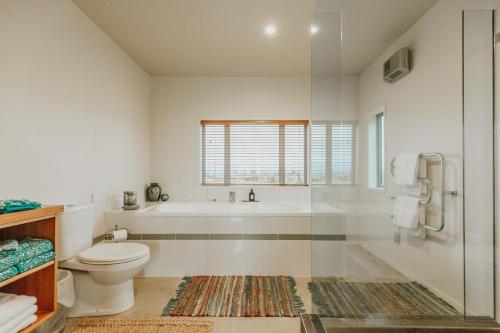 a white bathroom with a tub and a toilet at Appleby House & Rabbit Island Huts in Mapua