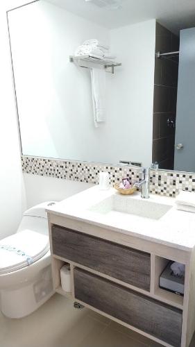 a bathroom with a sink and a toilet and a mirror at Hotel Festival Plaza Playas Rosarito in Rosarito