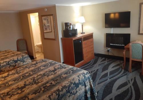 Habitación de hotel con 2 camas, escritorio y TV. en Rochester Inn, en Rochester