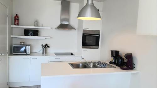 een witte keuken met een wastafel en een magnetron bij 19 Brussels Expo in Wemmel