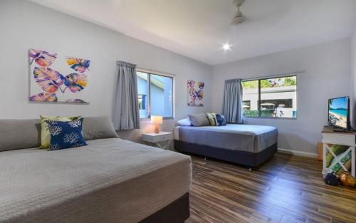a bedroom with two beds and a flat screen tv at Blue Water Views on Hamilton Island by HIHA in Hamilton Island