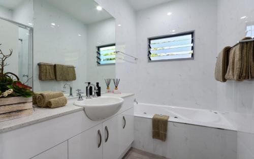 a white bathroom with a sink and a bath tub at Blue Water Views on Hamilton Island by HIHA in Hamilton Island