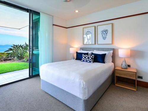a bedroom with a bed and a large window at Yacht Club Villas on Hamilton Island by HIHA in Hamilton Island
