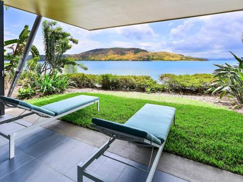 a patio with two chairs and a view of the water at Yacht Club Villas on Hamilton Island by HIHA in Hamilton Island