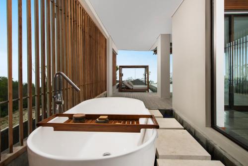 a bathroom with a bath tub on a balcony at Six Senses Uluwatu in Uluwatu