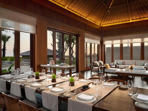a dining room with tables and chairs and windows at Six Senses Uluwatu in Uluwatu