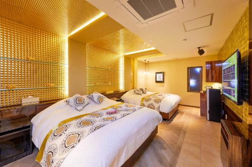 a hotel room with two beds and a flat screen tv at HOTEL Artia Nagoya (Adult Only) in Kitanagoya