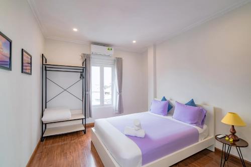 a bedroom with a large white bed with purple pillows at WECOZY HANOI - Railway Side, The Old Quarter in Hanoi