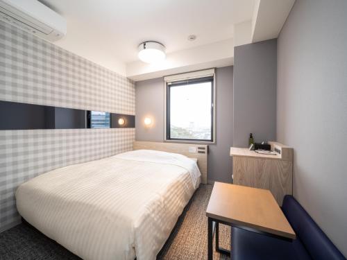 a small bedroom with a bed and a table at Super Hotel Anan City Hall Smoke-Free in Anan