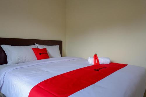 ein Bett mit einer roten und weißen Decke drauf in der Unterkunft RedDoorz near Terminal Mendolo Wonosobo in Wonosobo