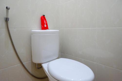 a red toy on top of a toilet in a bathroom at RedDoorz near Terminal Mendolo Wonosobo in Wonosobo