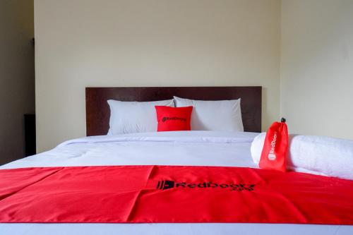 a red blanket on a white bed with red pillows at RedDoorz near Terminal Mendolo Wonosobo in Wonosobo