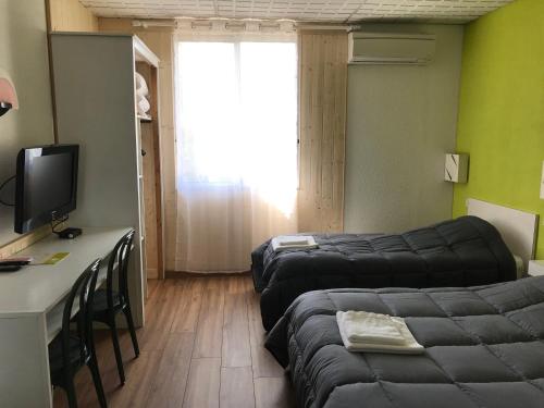 a room with two beds and a desk and a television at Hotel Les Chênes in Sisteron