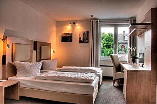 a hotel room with a bed and a desk and a window at Hotel Bartmanns Haus in Dillenburg