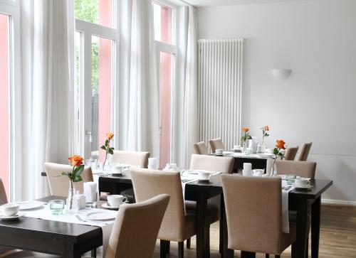 a dining room with tables and chairs and windows at Hotel Bartmanns Haus in Dillenburg