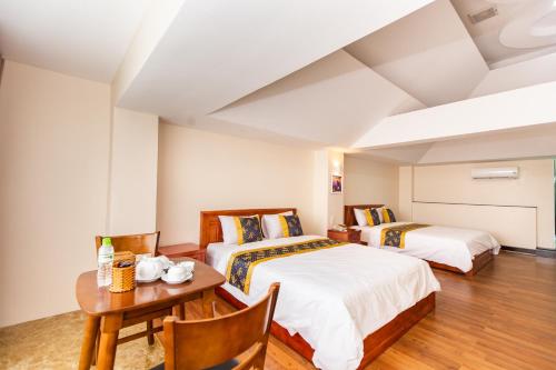 two beds in a room with a table and a desk at Hoa De Nhat Hotel- Sân Bay Tân Sơn Nhất in Ho Chi Minh City