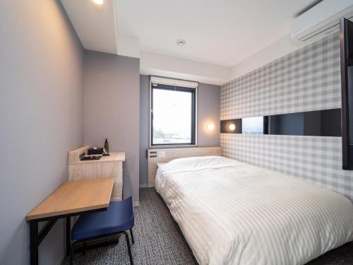 a bedroom with a bed and a desk and a window at Super Hotel Anan City Hall Smoke-Free in Anan