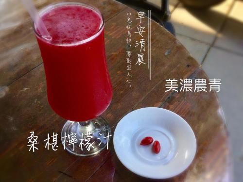 a red drink in a glass next to a white plate at Mei Nong Villa in Meinong