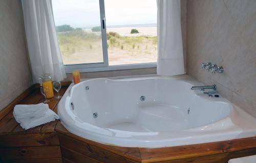 uma grande banheira branca numa casa de banho com uma janela em Marina de las Pampas em Mar de las Pampas