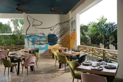 a restaurant with tables and chairs and a mural on the wall at Saman Boutique Hotel in Las Terrenas