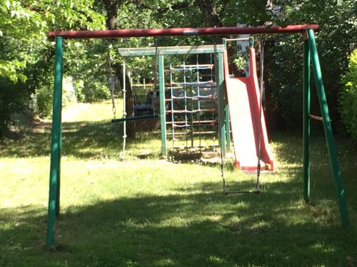 a playground with a slide in the grass at Hotel Les Chênes in Sisteron