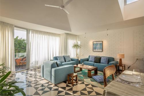a living room with blue couches and a table at El Arbol by The Blue Kite with Rooftop Pool, Kitchen, Wifi, Security,10 Mins to Candolim Beach & 5 mins to Casino in Panaji