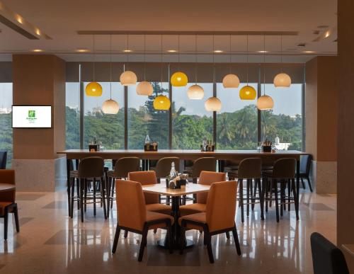 a restaurant with tables and chairs and large windows at Holiday Inn Bengaluru Racecourse by IHG in Bangalore