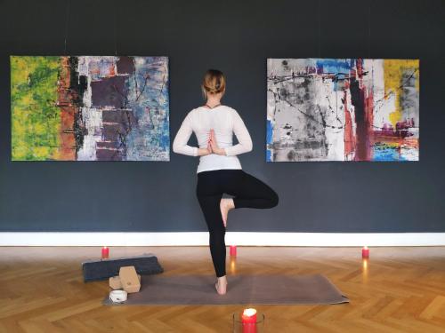 a woman in a yoga pose in front of two paintings at Gut Pohnstorf in Alt Sührkow
