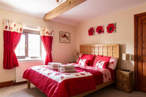 a bedroom with a red bed with red curtains at Herefordshire Holiday Cottages in Lea