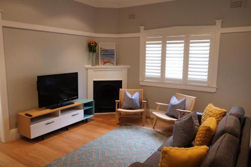 a living room with a couch and a television at Beach Retreat in Sydney