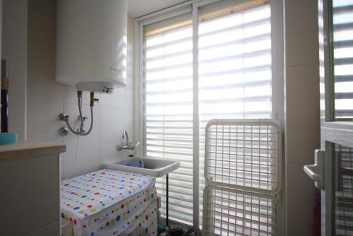 uma pequena casa de banho com um lavatório e uma janela em Apartamento planta baja Residencial Aquamarina by costablancarent em Denia