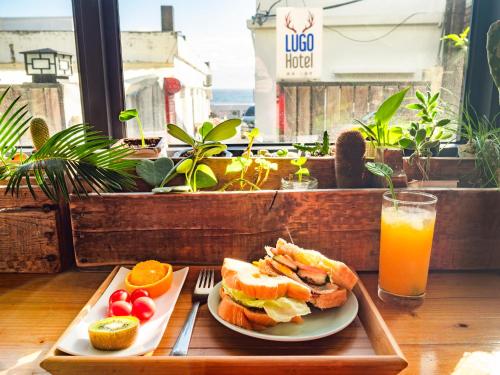 a tray with a sandwich and a glass of orange juice at Lugo Hotel in Manzhou