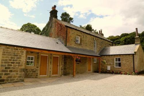 an old brick building with a driveway in front of it at Woodsome Hall Golf Club Cottage on the Course in Fenay Bridge