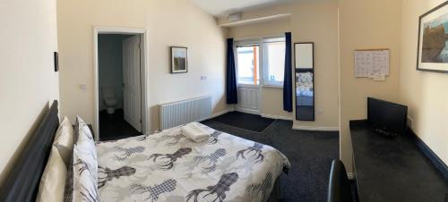 1 dormitorio con cama y escritorio. en Ivy Cottage-Serviced accommodation en Dyce