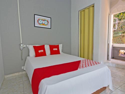 um quarto com uma cama com almofadas vermelhas e uma janela em OYO Hotel Castro Alves, São Paulo em São Paulo