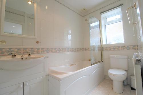 a white bathroom with a sink and a toilet at Spacious bungalow/private garden-sleeps up to 6 in Marple